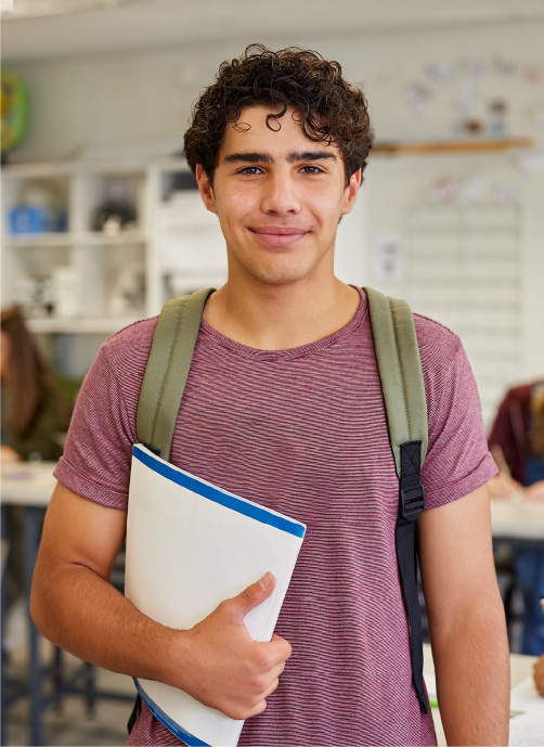 Jovem estudante branco de mochila nas costas e pasta na mão no corredor da faculdade